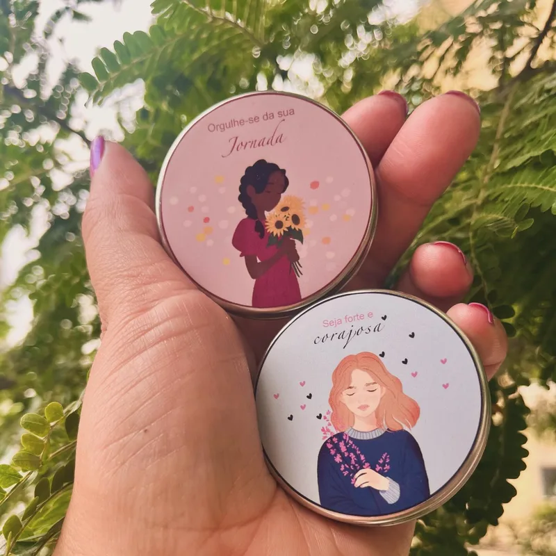 Duas latinhas ilustradas seguradas na mão, com folhagem ao fundo